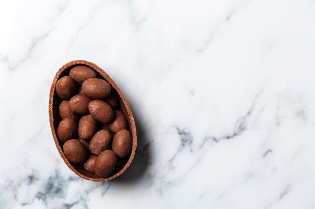 Chocolate easter egg filled with mini eggs on a marble background