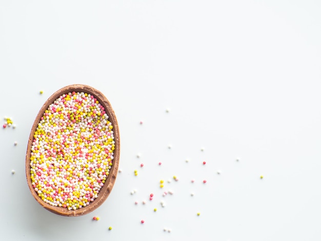 Chocolate easter egg with sweet sprinkles on white background