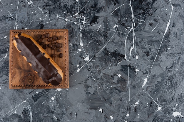 Chocolate eclair with coffee beans placed on a marble table.