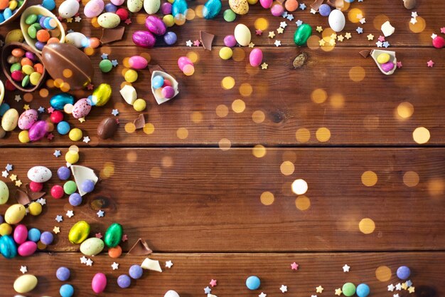 Photo chocolate eggs and candy drops on wooden table