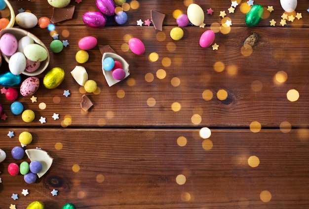 Photo chocolate eggs and candy drops on wooden table