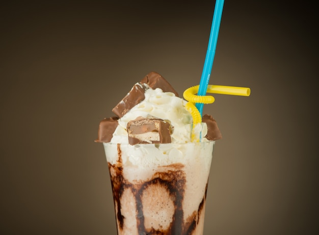 Chocolate fruit cocktail ice cream with straw on brown backlit background Summer tropical smoothie