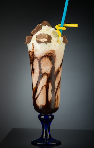 Chocolate fruit cocktail ice cream with straw on grey backlit background Summer tropical smoothie