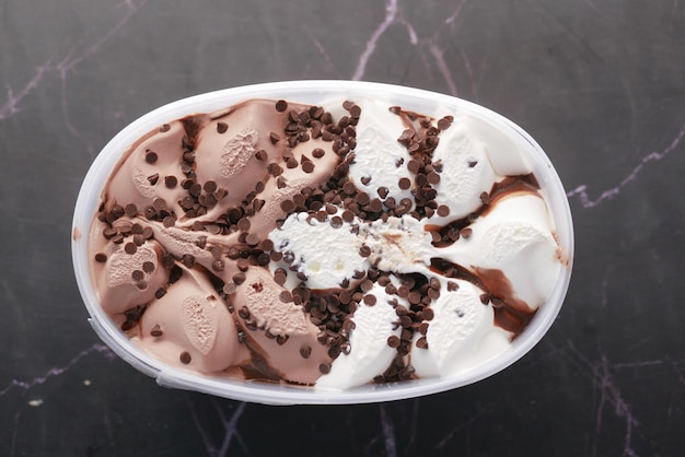 Chocolate ice cream in a plastic container on black