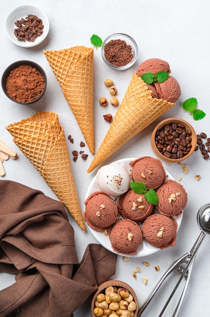 Chocolate ice cream with various additives and waffle cups on a gray background