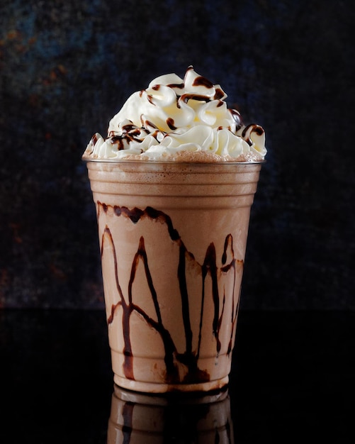 Chocolate milkshake served in a clear glass on a dark background Isolated drink