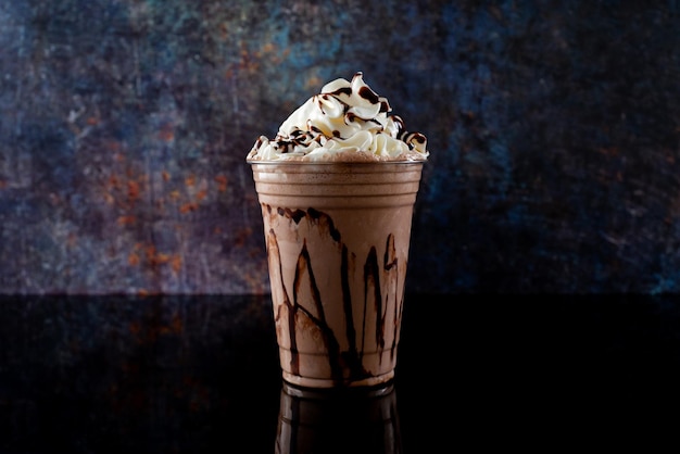 Chocolate milkshake served in a clear glass on a dark background Isolated drink