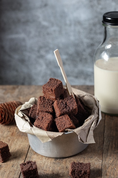 Chocolate mini brownie cake, dessert with milk on a dark background on a wooden table.