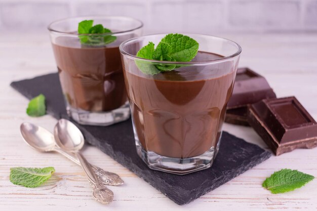 Chocolate mousse with mint leaves in glasses served on a black slate board