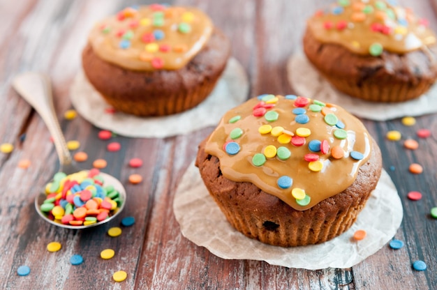 Chocolate muffins With caramel and multicolored tapping Geometry A wooden background is blurred