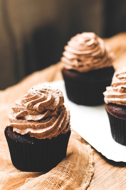 Chocolate muffins with cream on a wooden table. Homemade muffins. Sweet