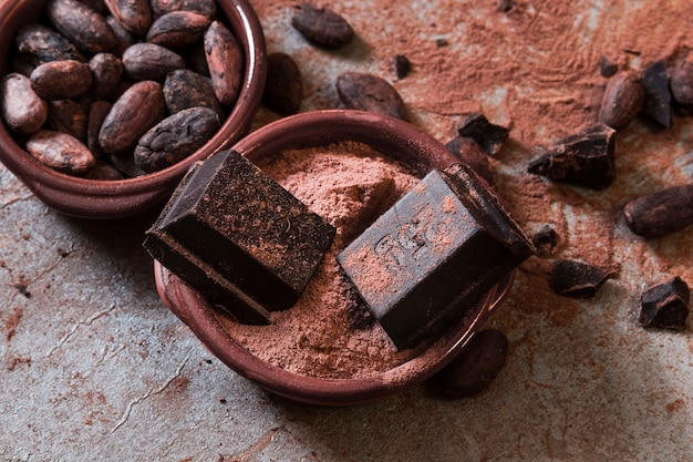 Chocolate pieces on cocoa powder and beans over the table