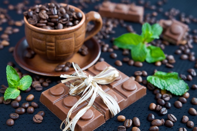 Chocolate pieces with mint leaves on black background