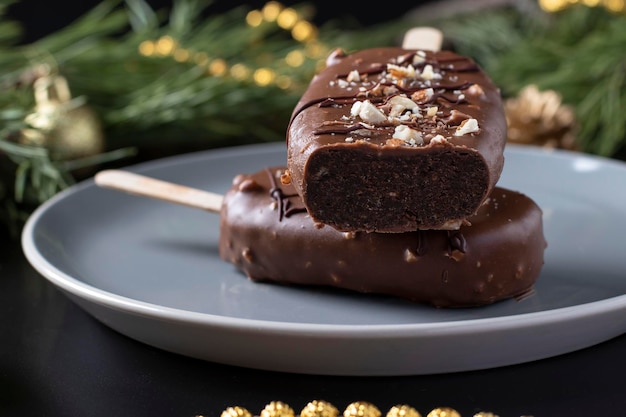 Chocolate popsicle cakes with nuts on a stick on a dark background