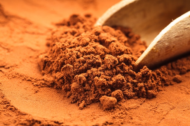 Chocolate powder heap and wooden scoop close up