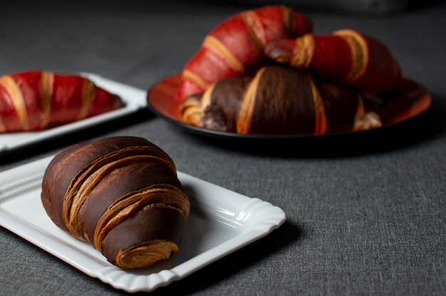 Chocolate and red croissants lie on plates on a gray cloth closeup buns