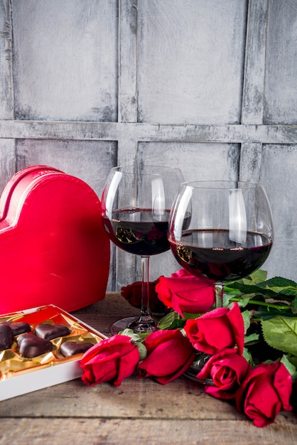 Chocolate, roses, wine glasses and heart box on wooden table