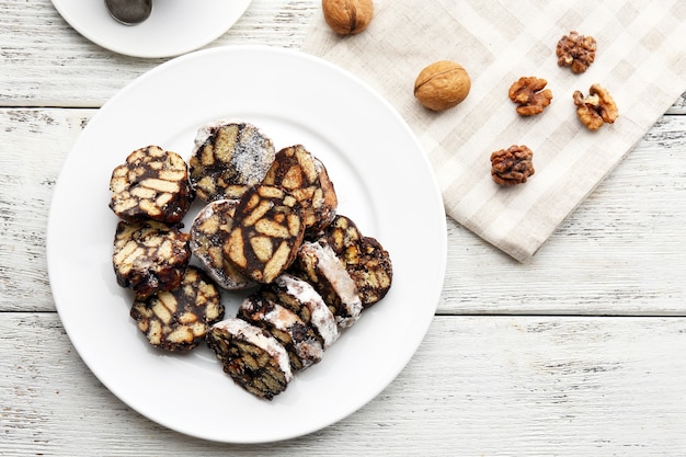 Chocolate salami in a plate over wooden background, close up