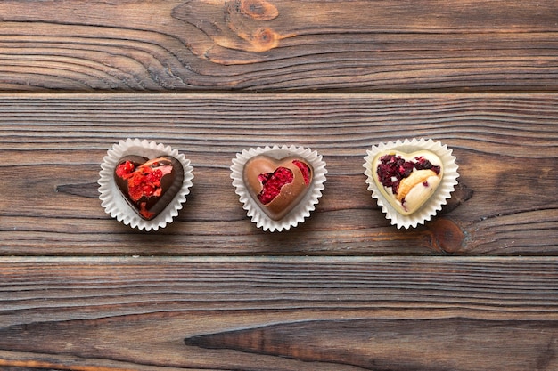 chocolate sweets in the form of a heart with fruits and nuts on a colored background top view with space for text holiday concept