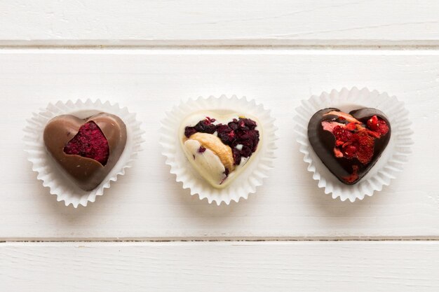 chocolate sweets in the form of a heart with fruits and nuts on a colored background top view with space for text holiday concept