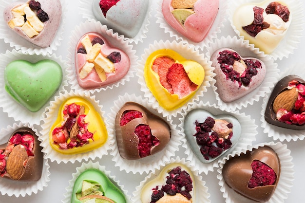 chocolate sweets in the form of a heart with fruits and nuts on a colored background top view with space for text holiday concept