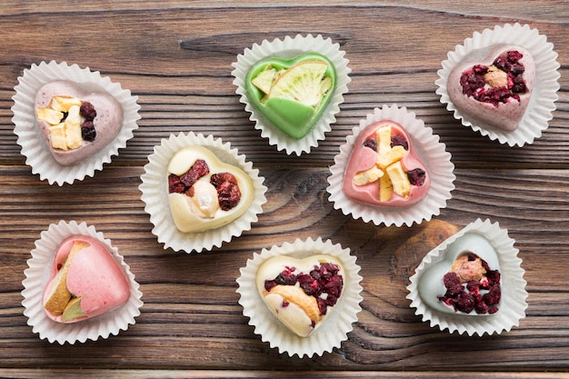 chocolate sweets in the form of a heart with fruits and nuts on a colored background top view with space for text holiday concept