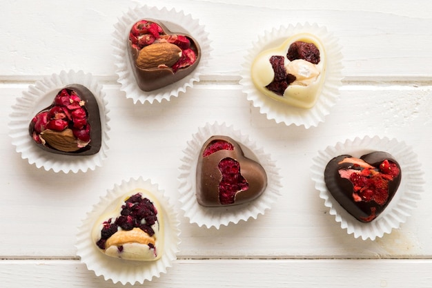 chocolate sweets in the form of a heart with fruits and nuts on a colored background top view with space for text holiday concept