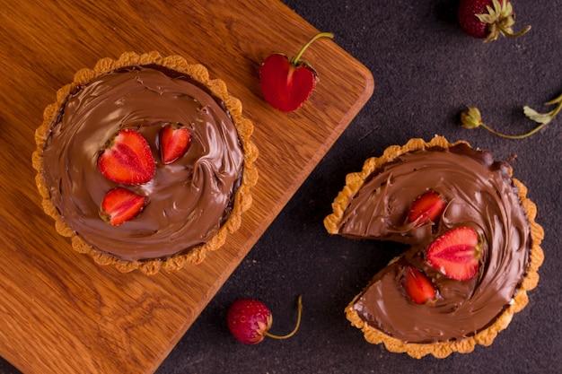 Chocolate tart with strawberries on a black background.