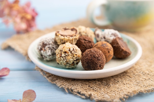 Chocolate truffle candies with cup of coffee on a blue wooden background side view close up selective focus