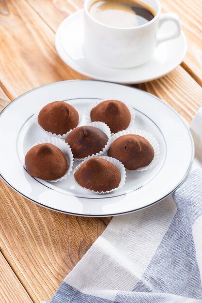 Chocolate truffles sweets in plate on wooden table close up