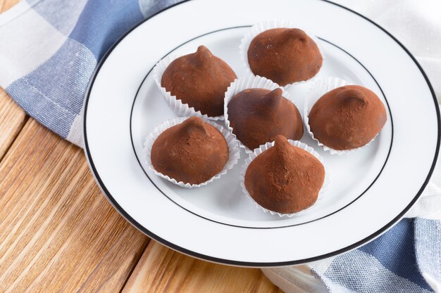 Chocolate truffles sweets in plate on wooden table