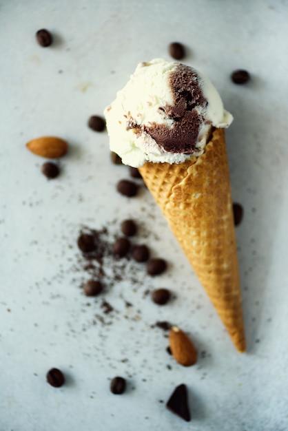 Chocolate, vanilla and coffee ice cream in waffle cone with coffee beans on grey stone . Summer food concept, copy space. Healthy gluten free ice-cream