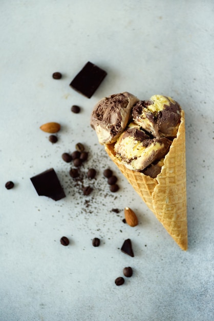 Photo chocolate, vanilla and coffee ice cream in waffle cone with coffee beans on grey stone