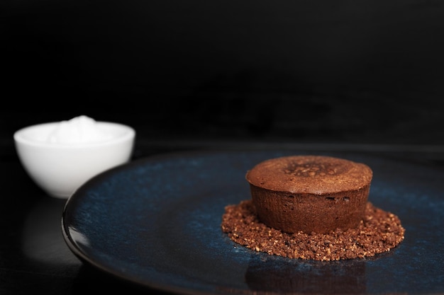 Chocolate volcano dessert on a blue plate next to ice cream on a black background