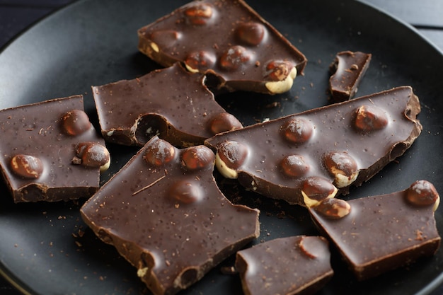 Chocolate with nuts on black Dark chocolate pieces closeup