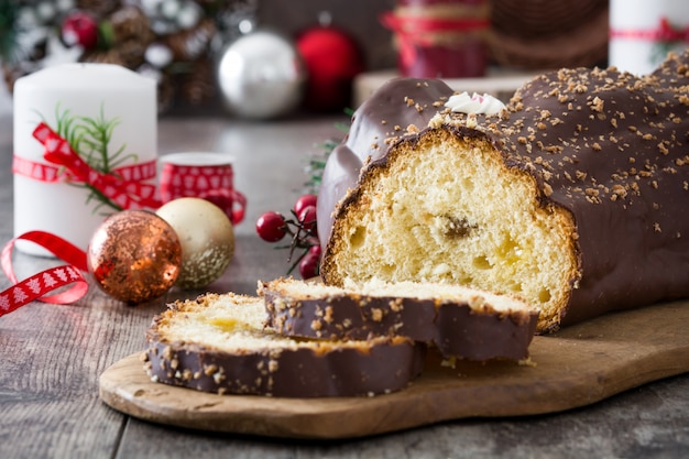 Chocolate yule log christmas cake and christmas ornament on wooden 