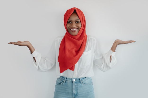 Choice balance concept Positive african american muslim woman holding something invisible on both palms