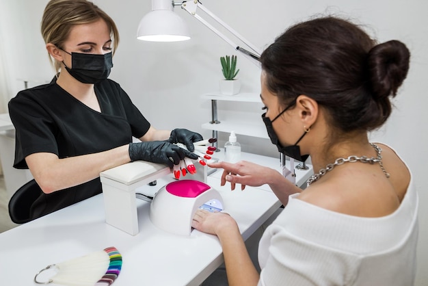 Choice of nail color A young girl chooses the color of her nails in a beauty salon Beauty and health of nails Manicure and client in a nail salon