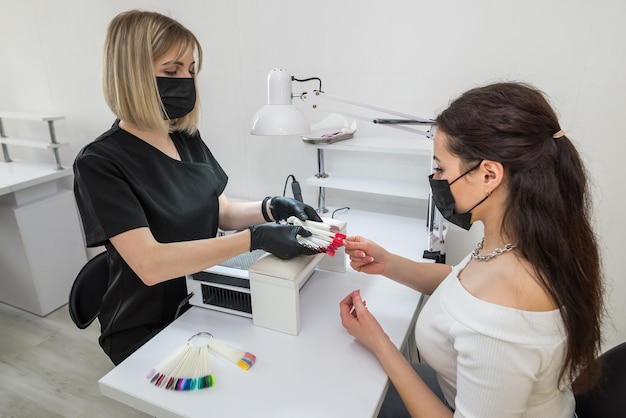 Choice of nail color A young girl chooses the color of her nails in a beauty salon Beauty and health of nails Manicure and client in a nail salon