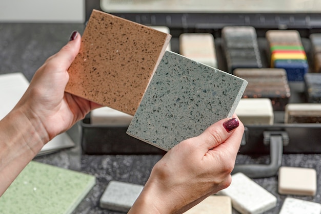 Choice of tiles female hands hold samples of tiles of different colors woman in store chooses bathro...