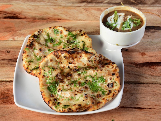 Chole Kulcha Clay baked stuffed Naan served with channa masala or chole masala typical meal of Amritsar India isolated over a rustic wooden background selective focus