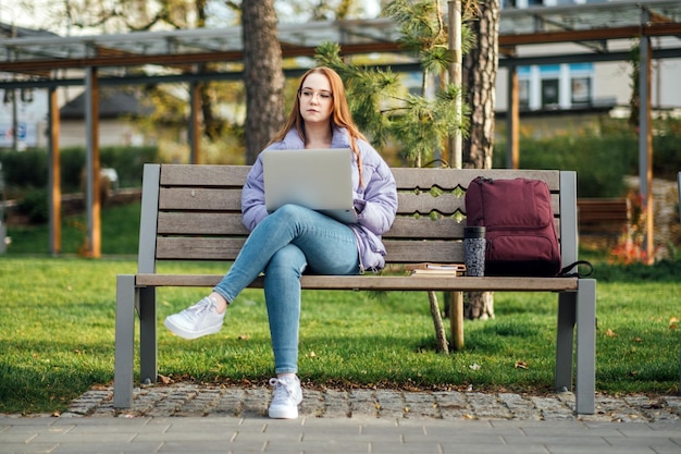 Choosing a university college female college student with books and laptop outdoors redhead college