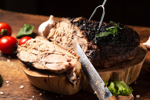 Chopped baked piece of meat with raw vegetables on a wooden background