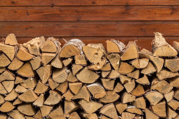 Chopped birch firewood on brown wooden wall background