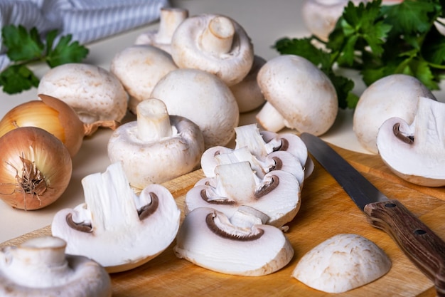 Chopped for champignons on cutting board with knife. Cooking in kitchen. Healthy and vegetarian food. Selective focus, top view.