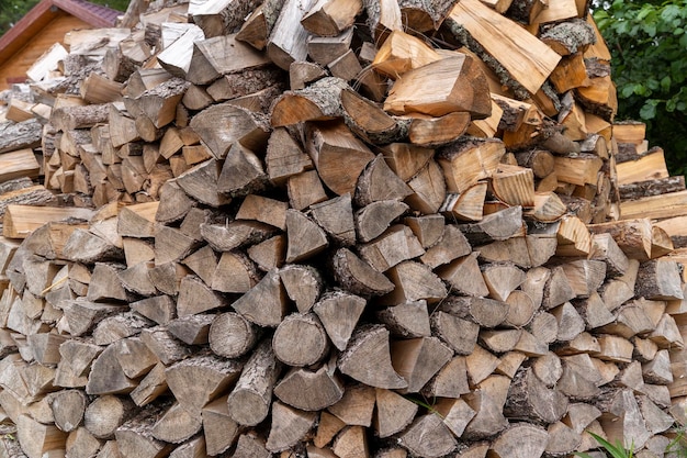 Chopped firewood stacked in a woodpile in the yard of the house