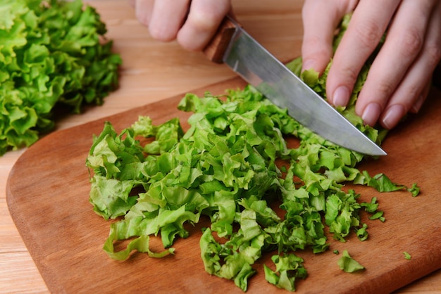 Photo chopped green lettuce on wooden board closeup