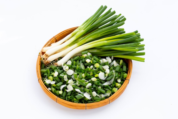 Chopped spring onions in bamboo basket on white background