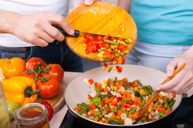 Chopped vegetables. Close-up of couple preparing food together