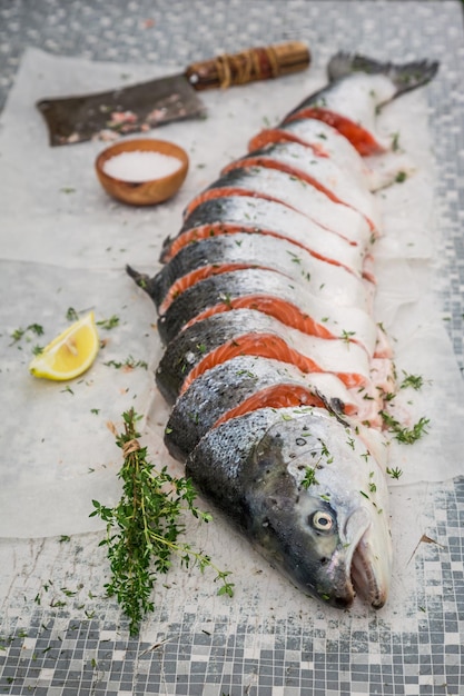 Chopping whole salmon with thyme and salt for grill